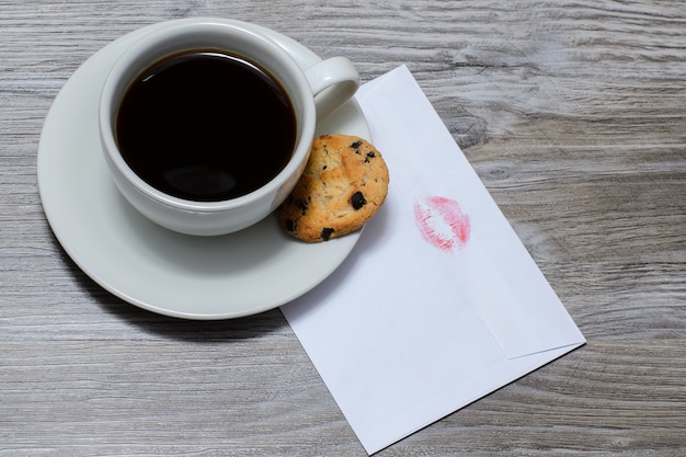 Una taza de café caliente en un platillo con una galleta de chocolate, carta