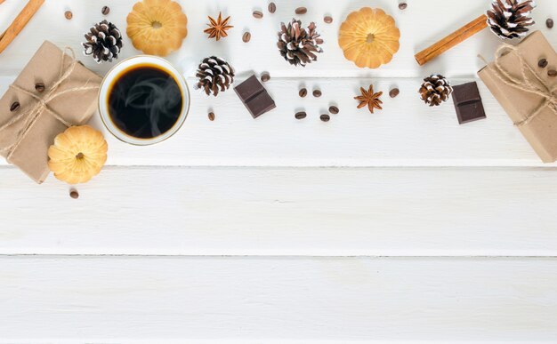 Taza de café caliente con repostería, paquetes de año nuevo y piñas