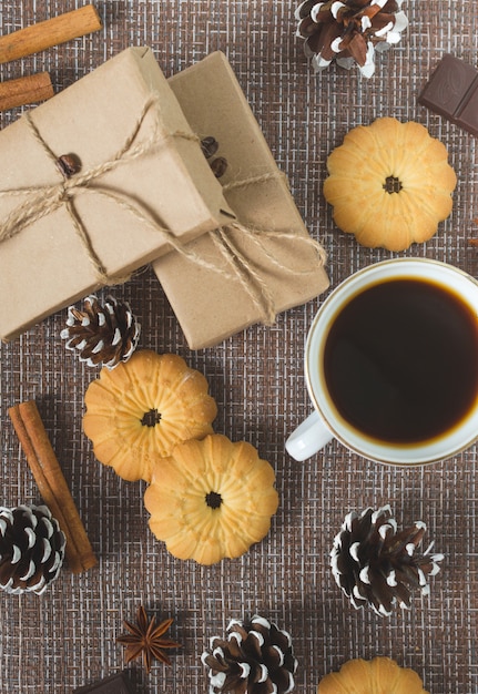 Taza de café caliente con repostería, paquetes de año nuevo y piñas