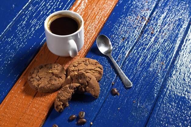 Foto taza de café caliente con sabrosas galletas de chocolate en una colorida mesa de madera