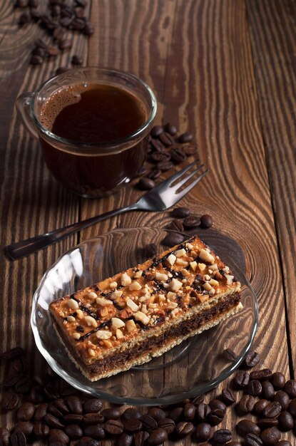 Taza de café caliente y sabroso pastel de caramelo con nueces en la mesa de madera antigua