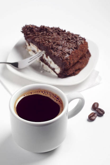 Taza de café caliente y tarta de chocolate sobre fondo blanco.