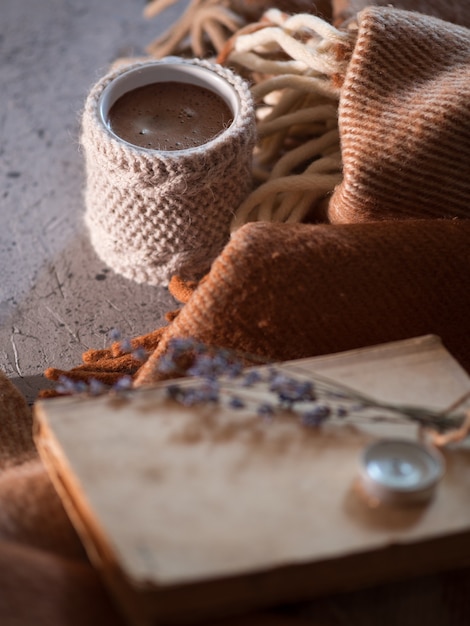 Foto una taza de café caliente tejida sobre una manta caliente y un libro viejo