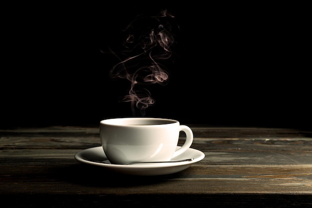 Taza de café caliente con vapor sobre fondo oscuro. imagen tonificada.