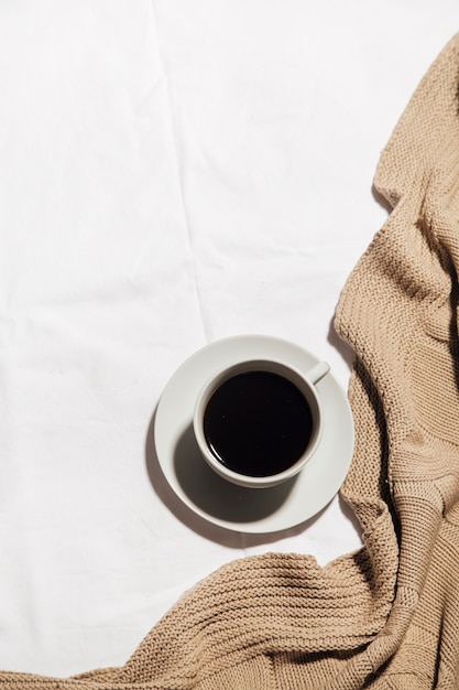 una taza de café en una cama blanca