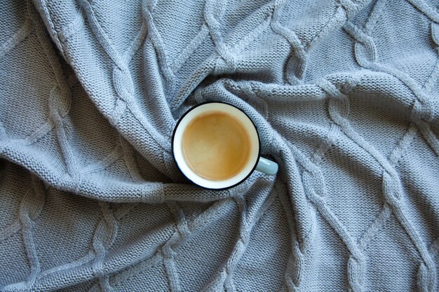 Taza de café en la cama con cuadros cálidos. Copie el espacio. Endecha plana, vista superior