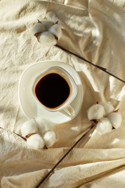 Taza de café en la cama con flores de algodón estado de ánimo matutino Ropa de cama textil de algodón orgánico y natural espacio de copia