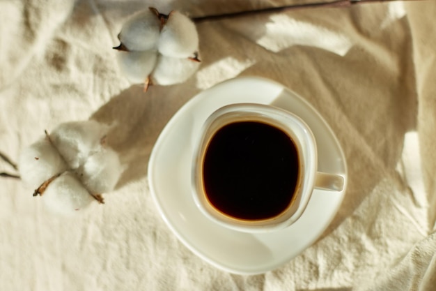 Taza de café en la cama con flores de algodón estado de ánimo matutino Ropa de cama textil de algodón orgánico y natural espacio de copia