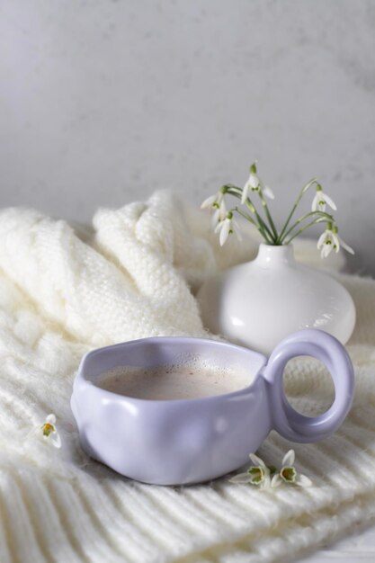 Una taza de café con campanillas a un lado.