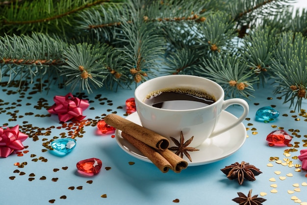 Una taza de café con canela sobre un fondo de ramas de abeto, confeti y juguetes. Composición de Navidad y año nuevo con café.