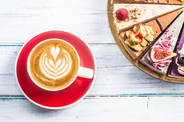 Una taza de café cappiciino artístico y mini pasteles crudos.