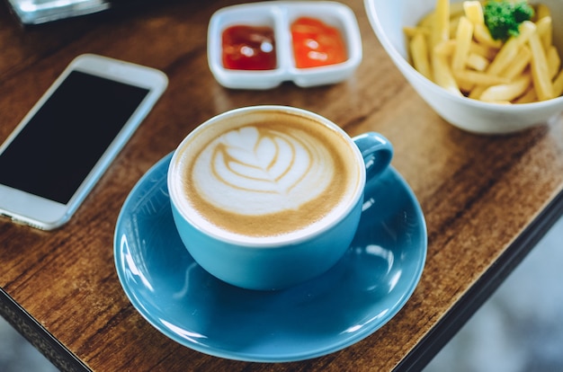 Taza de café capuchino azul sobre la mesa