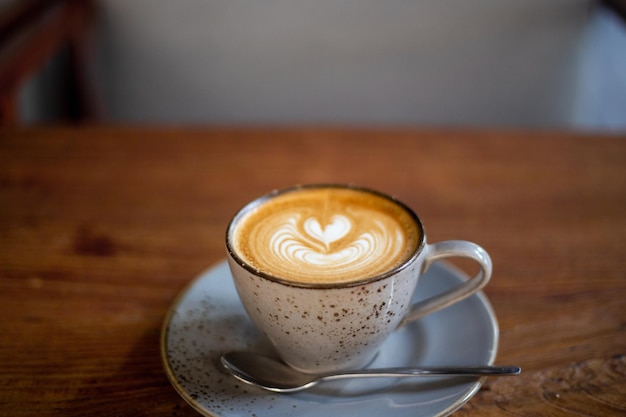 Taza de café capuchino caliente con arte latte en forma de corazón en una mesa de madera vieja marrón en el café