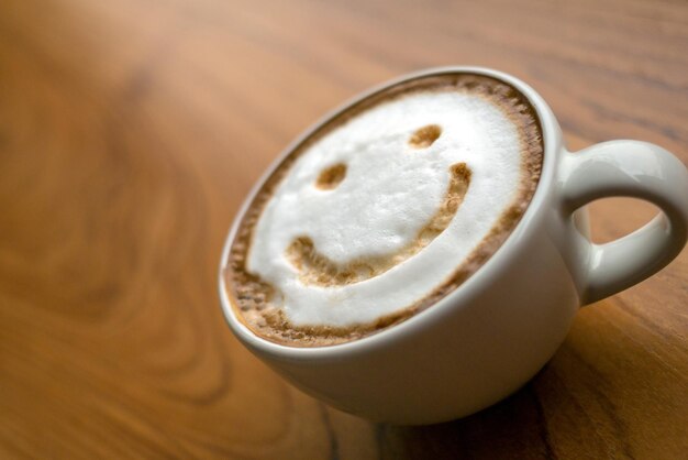 Una taza de café capuchino un delicioso café caliente con leche espumosa y una sonrisa en el fondo de color