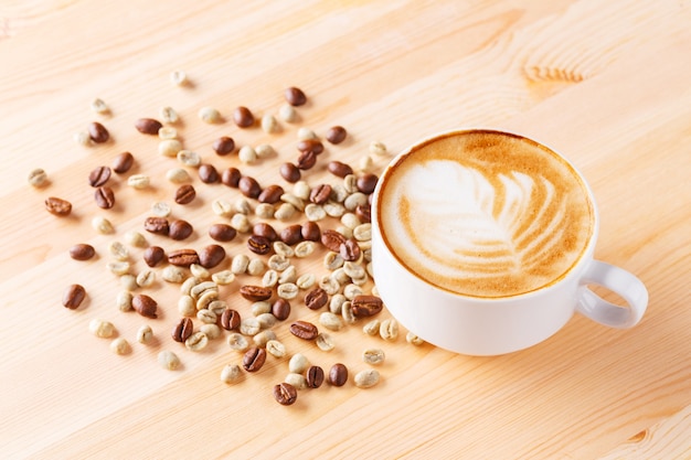 Foto taza de café capuchino con frijoles en la mesa