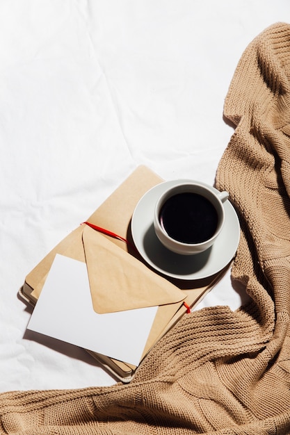 Taza de café con carta y bloc de notas abierto aislado sobre fondo blanco.
