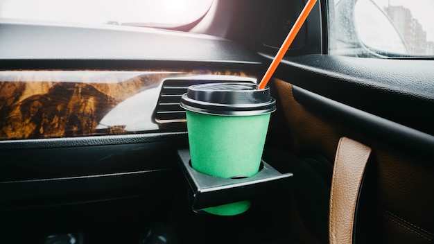 taza de café de cartón verde en el coche en las manos beber en el viaje