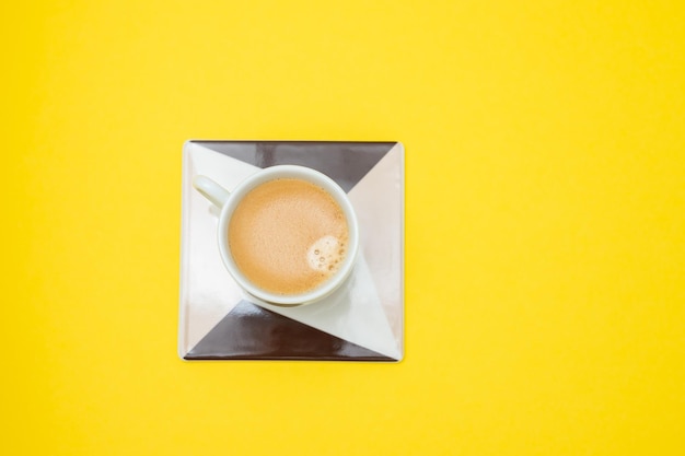 Taza de café en cerámica sobre papel amarillo