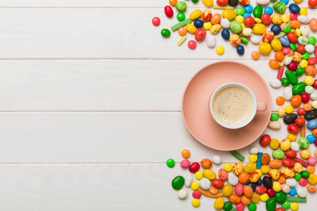 Taza de café con chocolates y dulces de colores Vista superior en el fondo de la mesa con espacio de copia