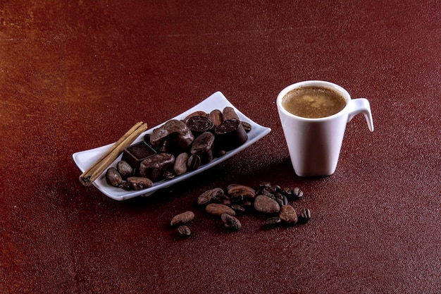 Taza de café con chocolates fotografiada sobre fondo pintado de marrón