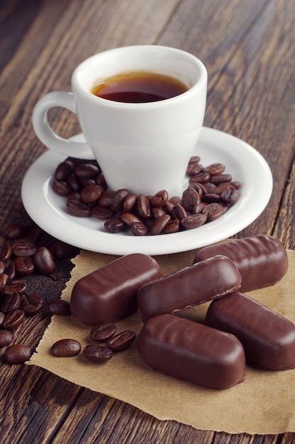 Taza de café con chocolates sobre mesa de madera rústica