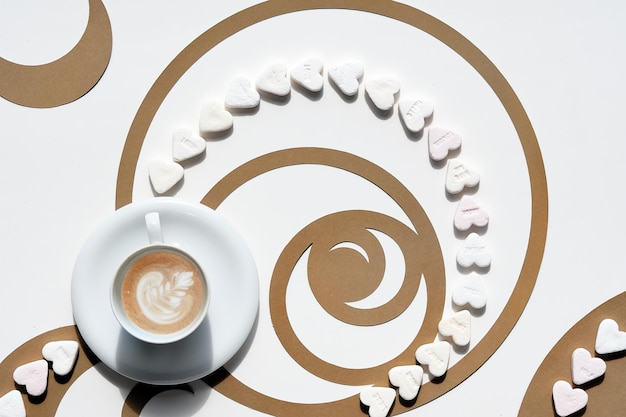 Taza de café Círculos de secuencia de Fibonacci hechos de papel marrón y corazones de azúcar Arte latte con diseño floral perfección sabrosa Arte de papel conceptual de proporción áurea Vista superior en blanco y marrón