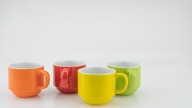 Taza de café colorida sobre fondo de papel de colores Una gran cantidad de tazas para café y té en la cafetería Concepto de fondo de comida y bebida