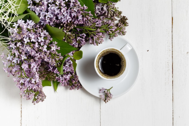 Taza de café y coloridas flores de color lila en la mesa de jardín