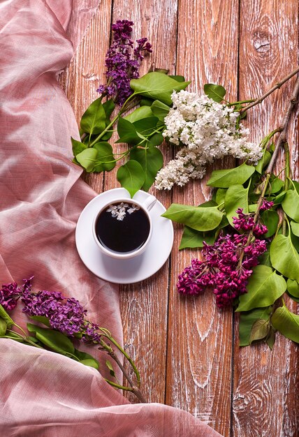 Taza de café y coloridas flores lilas en la mesa de madera del jardín.