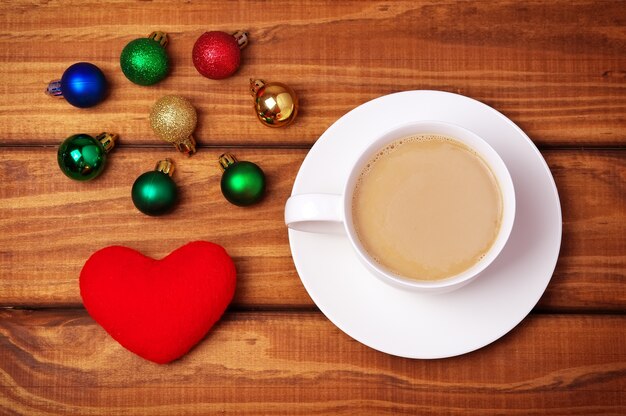 Taza de café, corazón y burbujas navideñas sobre fondo de madera.