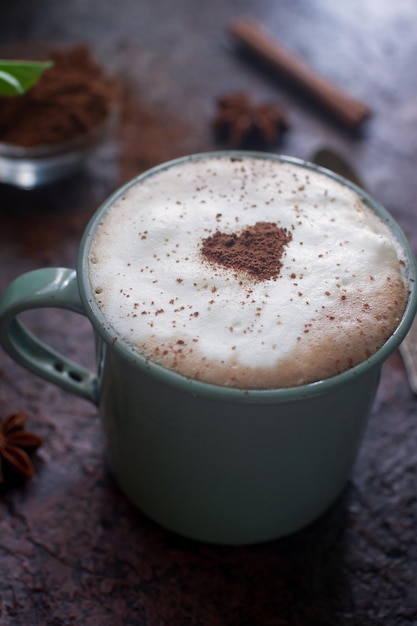 Taza de café con corazón de canela de cacao para el desayuno en la mesa de piedra oscura