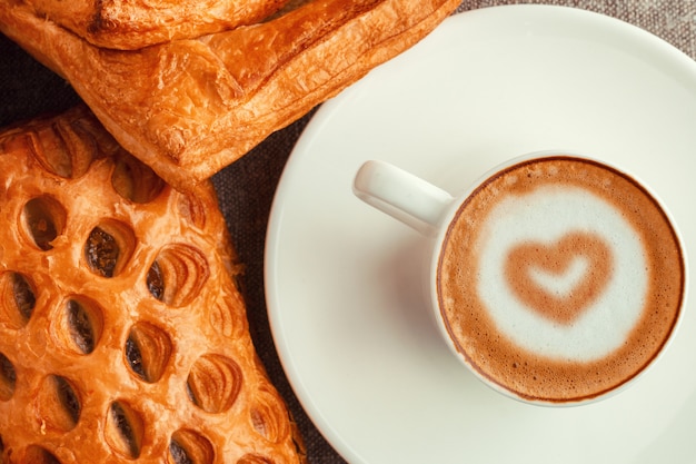 Una taza de café con un corazón y pasteles.