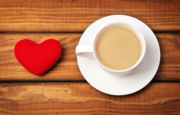 Taza de café y corazón sobre fondo de madera.