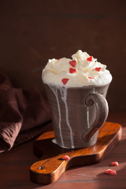 Taza de café con crema batida y corazones rojos