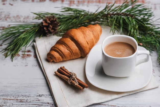 Taza de café y un croissant en la mesa. El concepto de una tarjeta de felicitación navideña