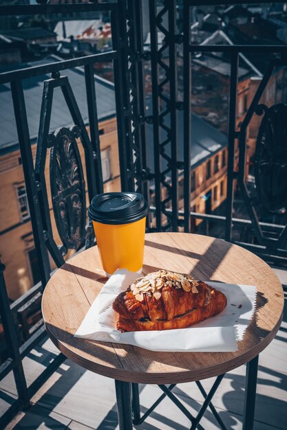 Taza de café y croissant recién horneado en un plato sobre una mesa de madera para el desayuno francés por la mañana en un balcón