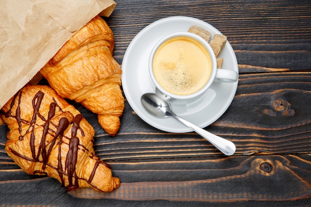 Taza de café y croissant sobre fondo de madera