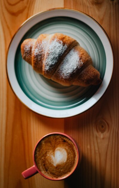 Una taza de café y un croissant sobre una mesa con una taza de café.