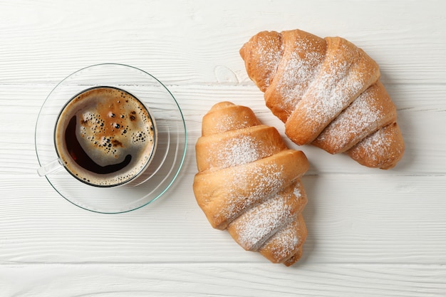 Taza de café y croissants sobre fondo de madera, vista superior