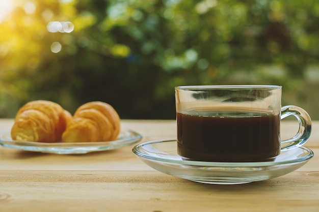 Una taza de café y cruasanes en fondo natural verde borrosa