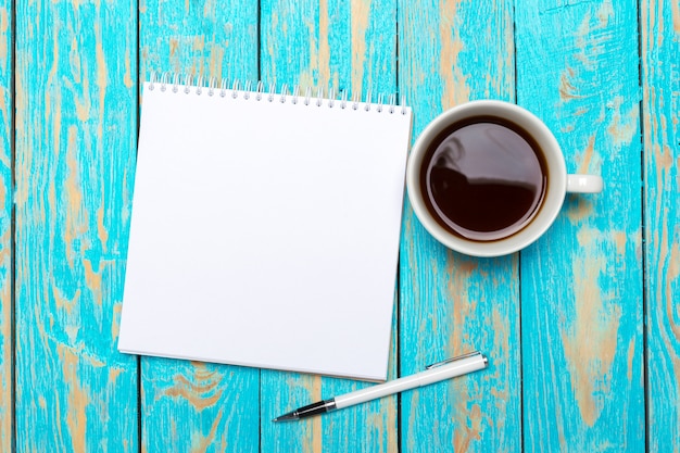 Taza de café con el cuaderno en el escritorio de madera