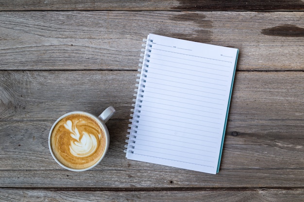 taza de café con el cuaderno en la mesa de madera