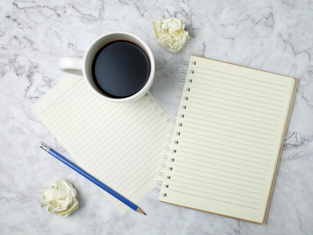 Taza de café con cuaderno sobre fondo de textura de mármol