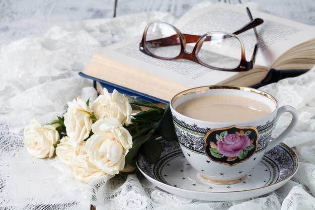 Taza de café con cuaderno y vasos en la mesa de madera