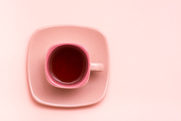 Taza de café cuadrada con una bebida rosa en un platillo