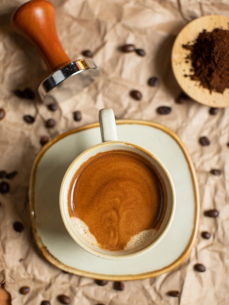 Una taza de café con una cuchara al lado y granos de café en un plato.