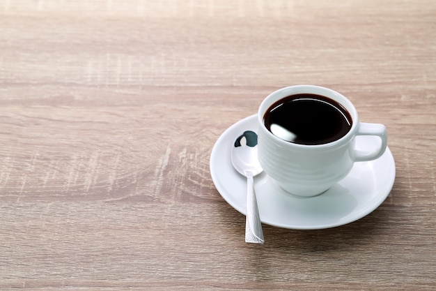 Taza de café y cuchara en mesa de madera
