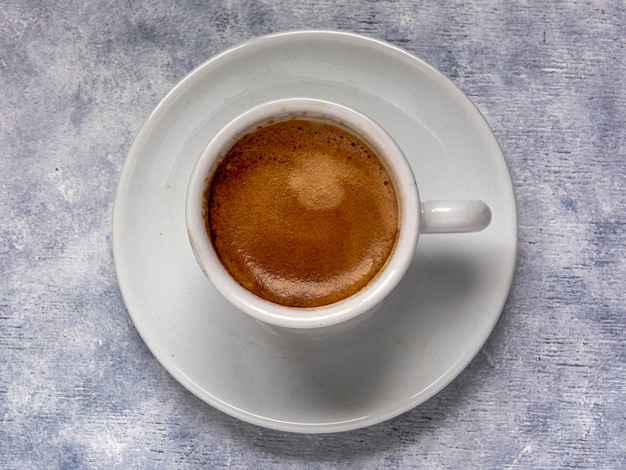 Taza de café con cuchara sobre una superficie texturizada blanca.