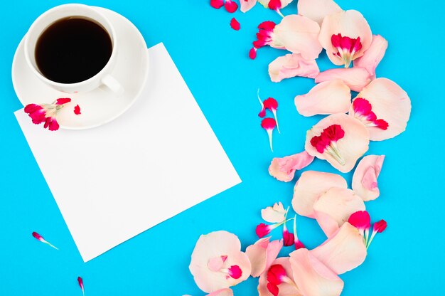 Taza de café con decoración de flores en la mesa de color azul claro. Concepto de amor y romance.