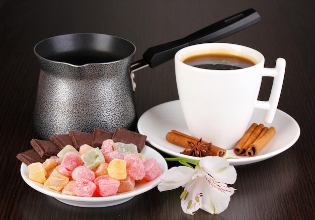 Taza de café con delicias rahat y cafetera sobre mesa de madera